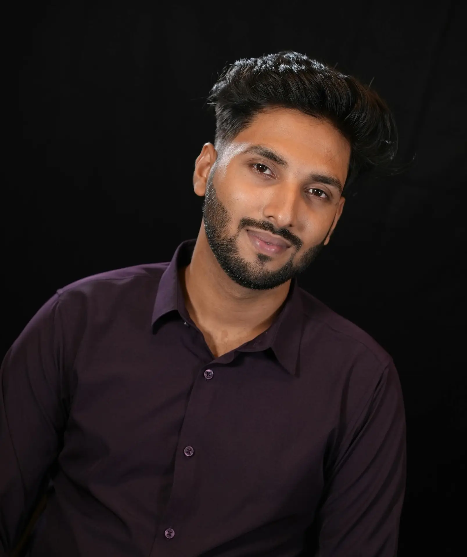 Headshot of a man with a dark background behind him.